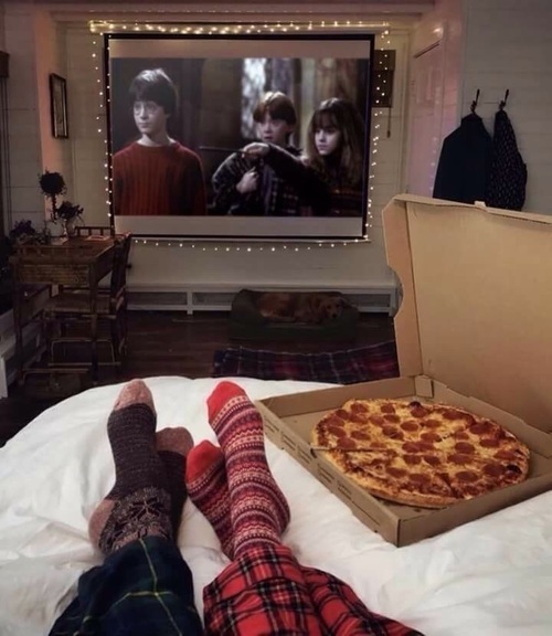 Pareja de novios viendo una película y comiendo pizza