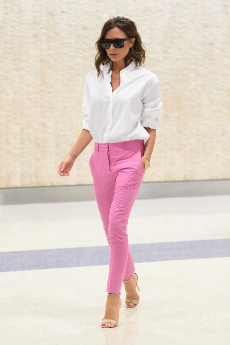 Victoria Beckham usando un pantalón rosa y camisa blanca 