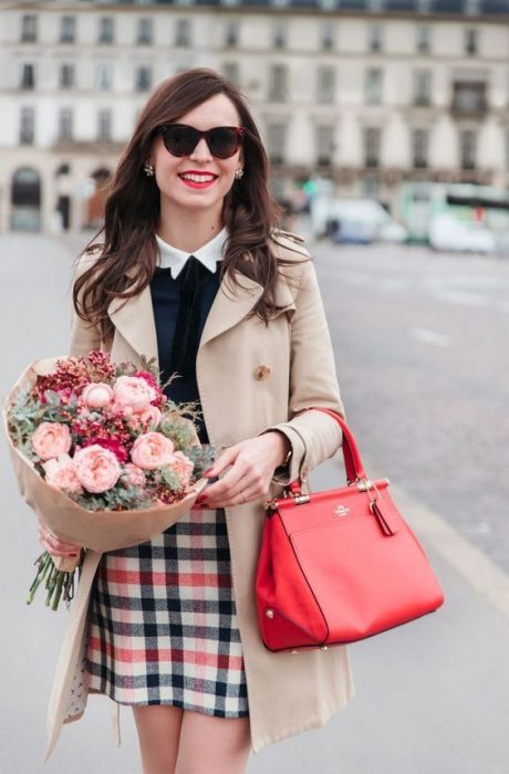 Chica sosteniendo un ramo de flores y un bolso rojo 