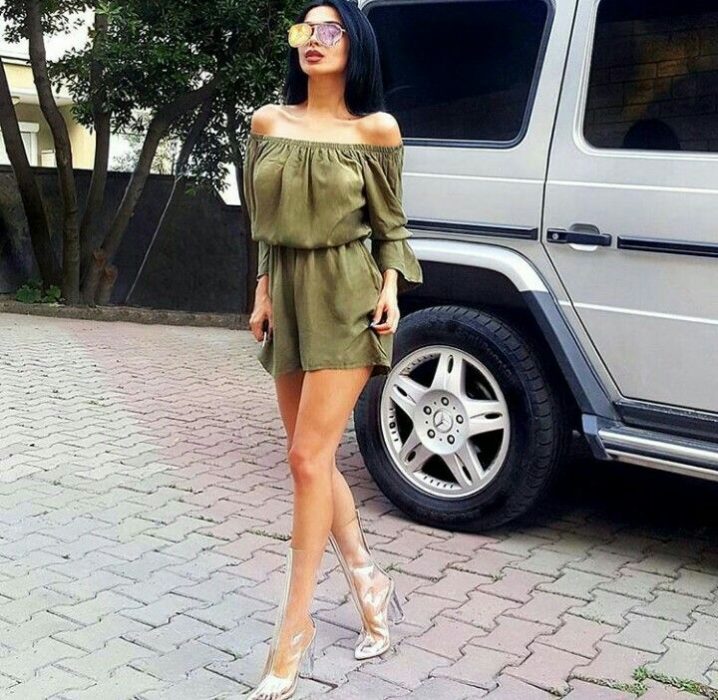 Chica usando un vestido verde con unas botas transparentes 