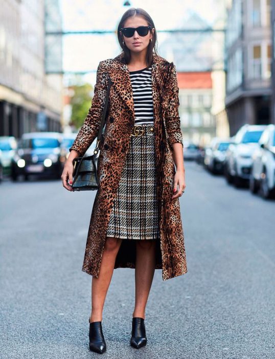 Chica usando una falda a cuadros, blusa a rayas y saco de animal print leopardo 