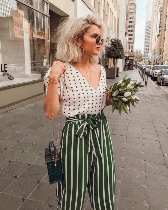 Chica usando un pantalón verde con líneas y una blusa blanca con puntos 