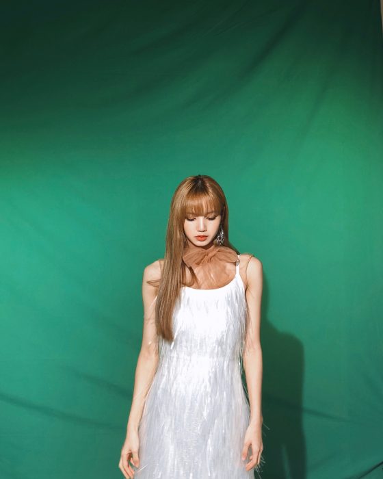 mujer con vestido blanco con flecos y fondo verde 