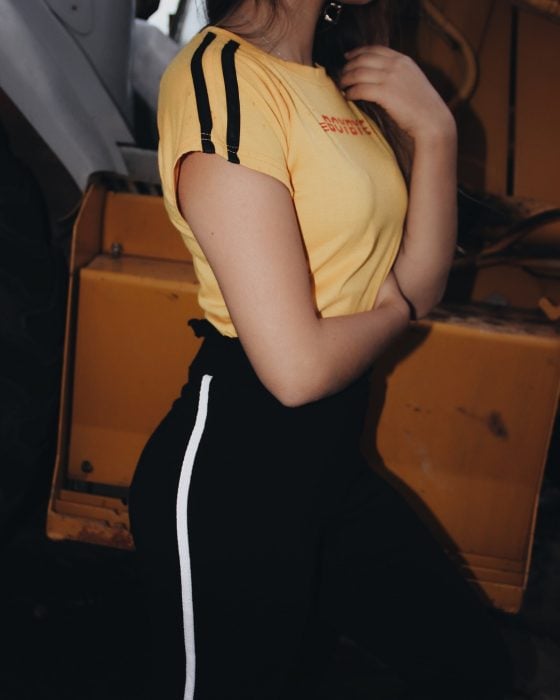 mujer con pantalon negro de rayas y playera amarilla 