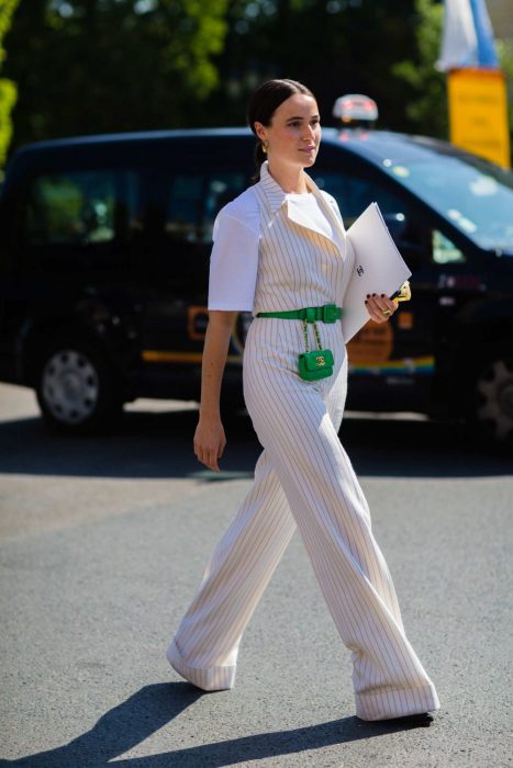 Chica usando una mini bolsa de color verde con un traje blanco