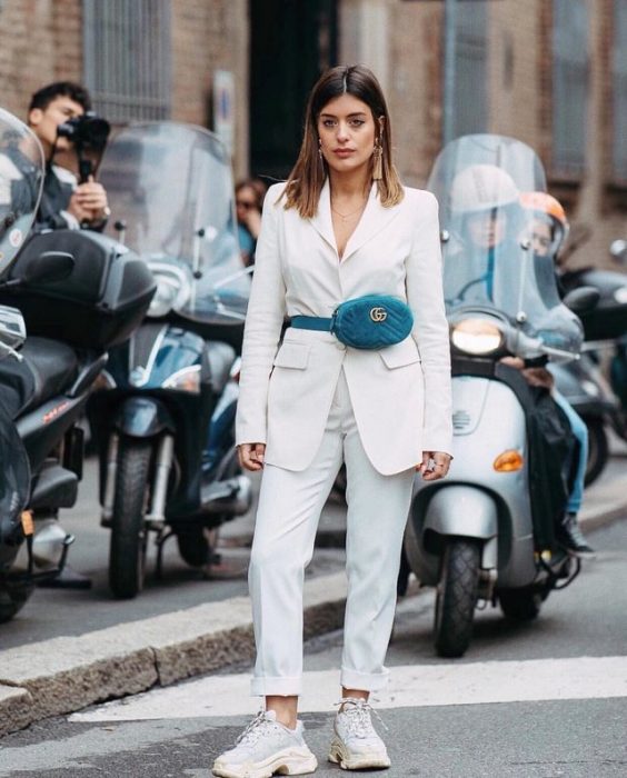 Chica usando un traje blanco con una bolsa riñonera color azul