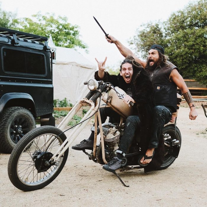 Jason Momoa sobre una motocicleta conducida por uno de sus amigos