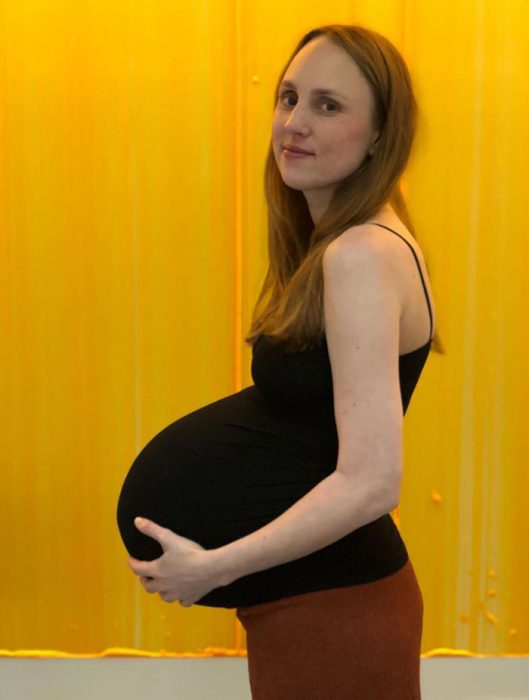 Mujer embarazada de trillizos parada frente a la cámara 