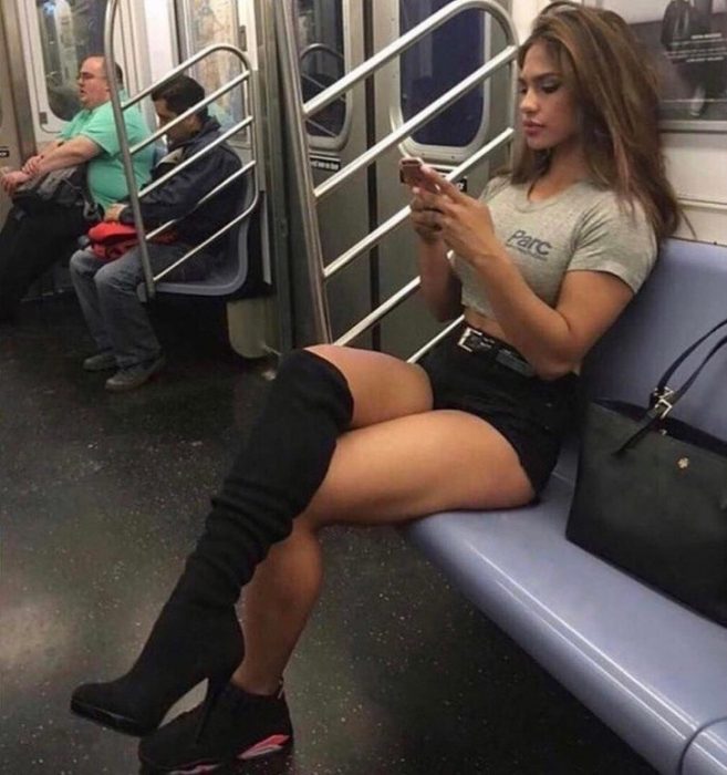 Mujer sentada en el metro usando una zapatilla y una bota 