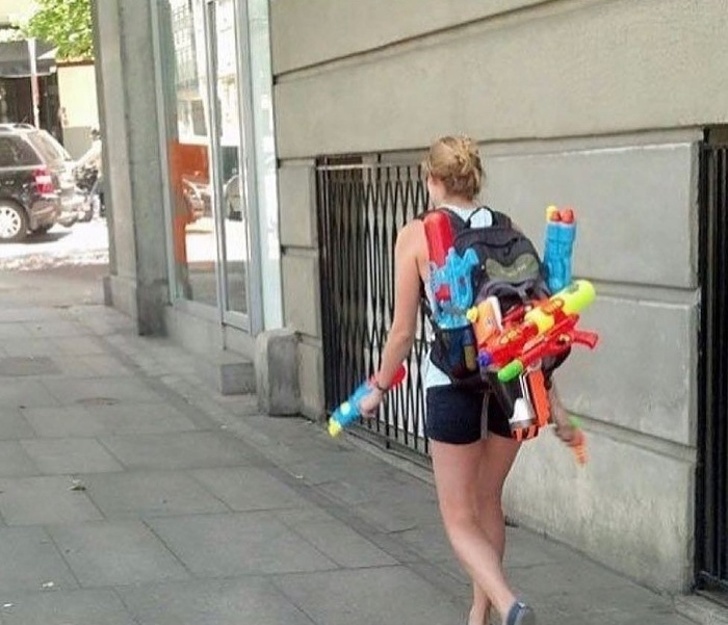 Mujer caminando por la calle mientras sostiene pistolas de agua