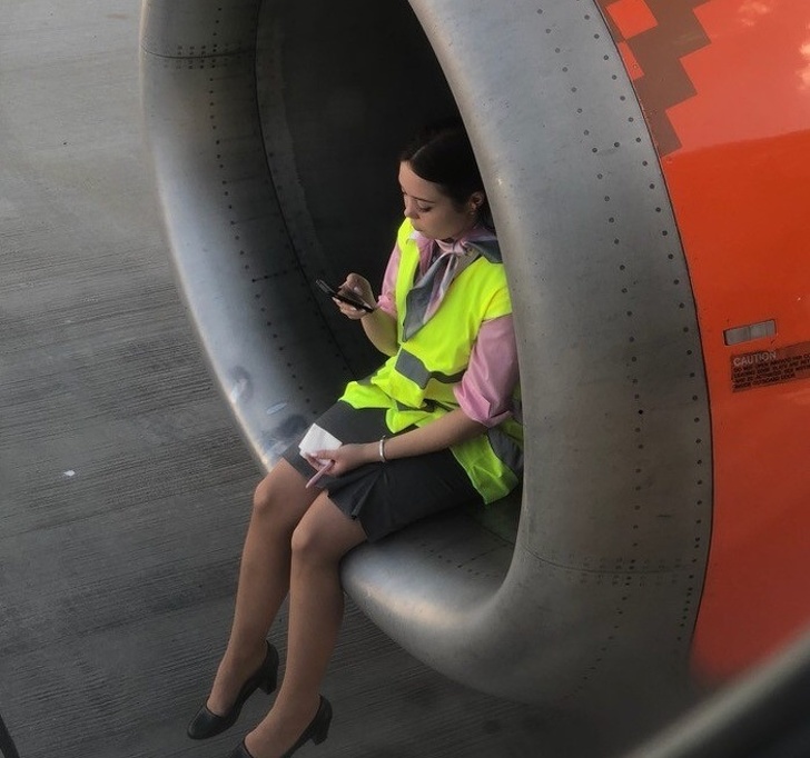 Mujer sentada en una turbina de avión mientras revisa su celular