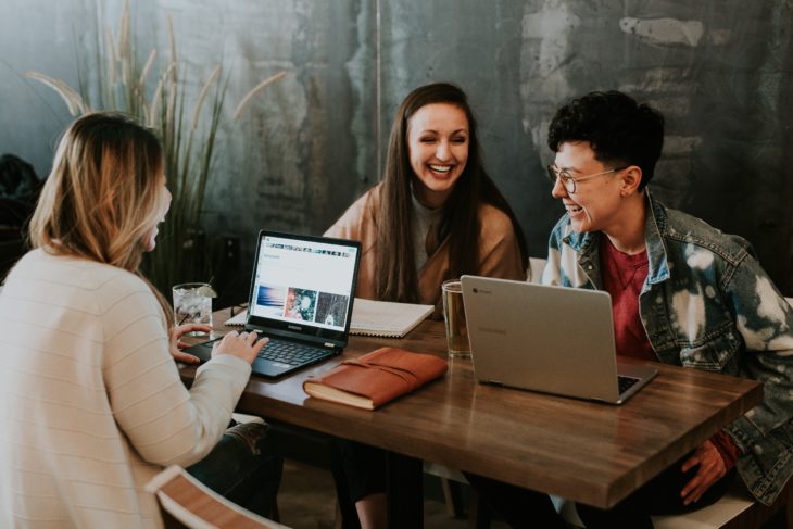 compañeras de trabajo platicando frente a sus computadoras