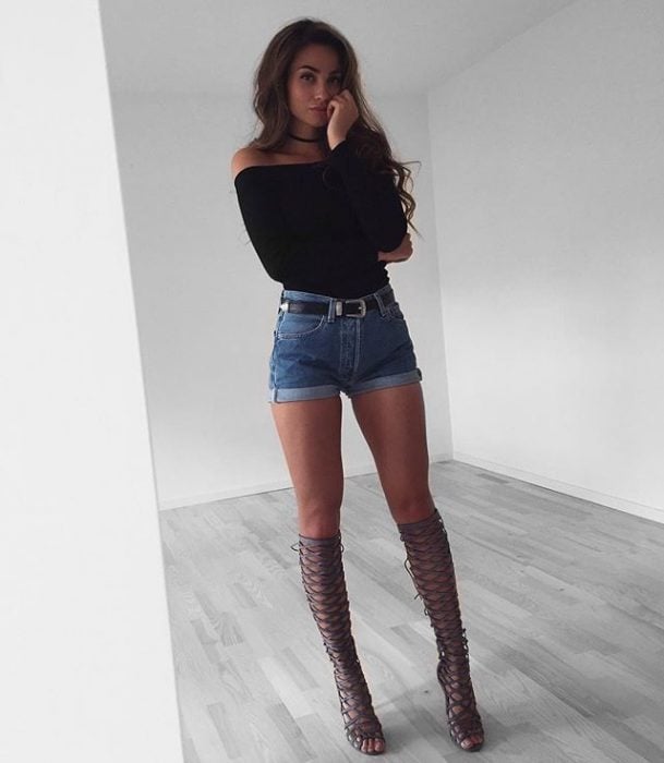 Chica usando un short, top y botas de color negro 