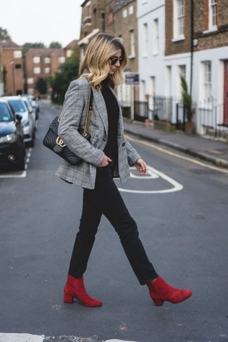Chica caminando por la calle mientras usa unas botas de tacón cuadrado