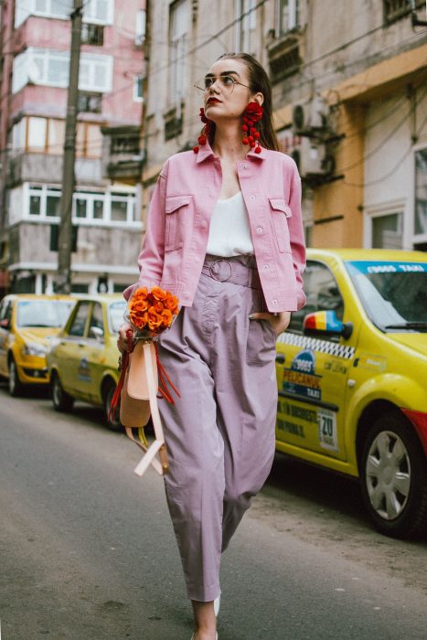 mujer con chaqueta rosa pastel y aretes rojos 