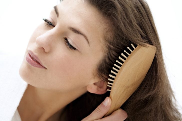 Mujer cepillándose el cabello con cepillo de madera