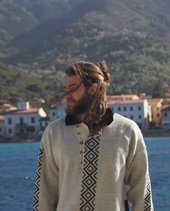 Hombre de cabello largo posando junto al mar