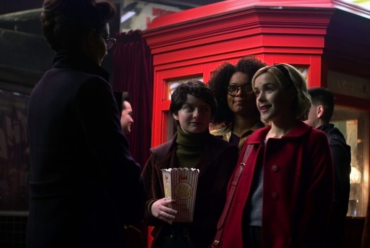 Tres amigas felices saliendo del cine y hablando con una mujer adulta