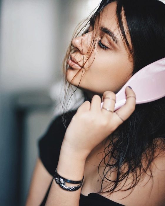 Mujer con los ojos cerrados cepillándose el cabello