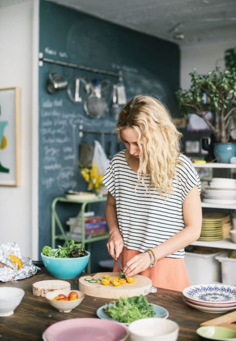 Mujer de cabello rubio y ondulado con blusa a rayas preparando de comer