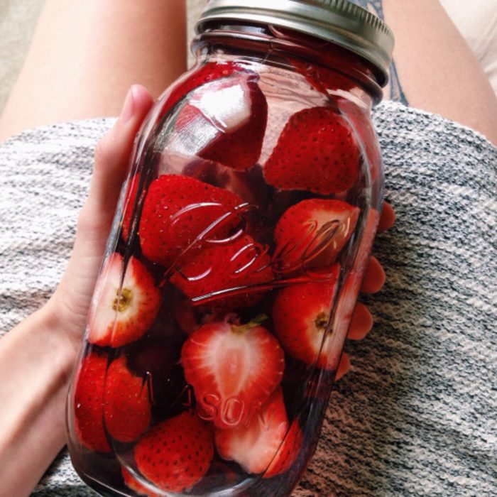 Mujer sosteniendo un frasco de vidrio con fresas partidas