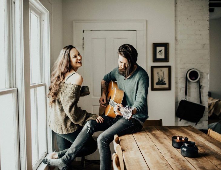 Novio toca la guitarra mientras novia sonrie feliz