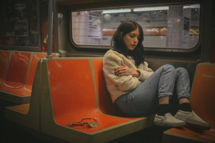Mujer con semblante triste en un asiento del metro