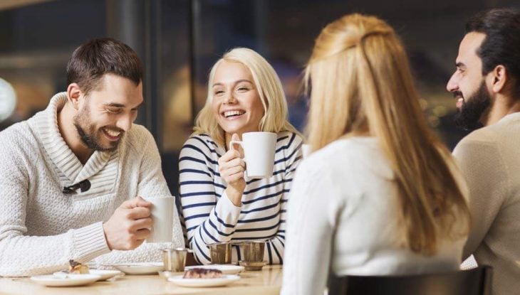 Mujeres y hombres riendo mientras beben café