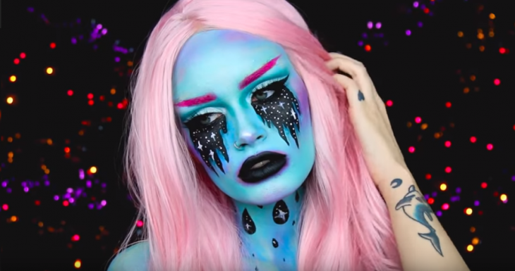 mujer con maquillaje azul de alien y cabello rosa 