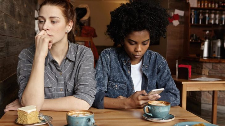 Amigas revisando su celular durante una salida al café