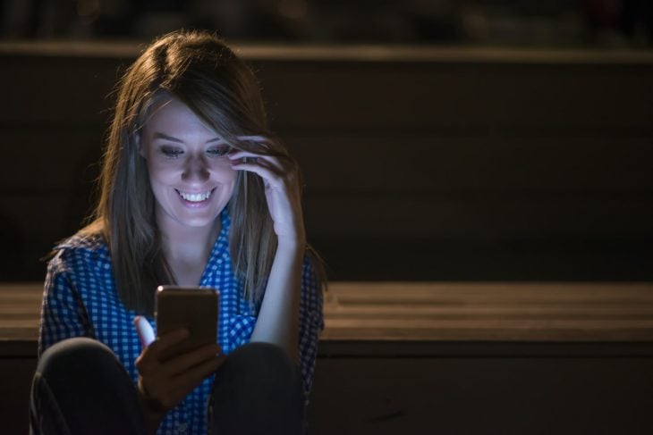 Mujer revisando su celular en la noche