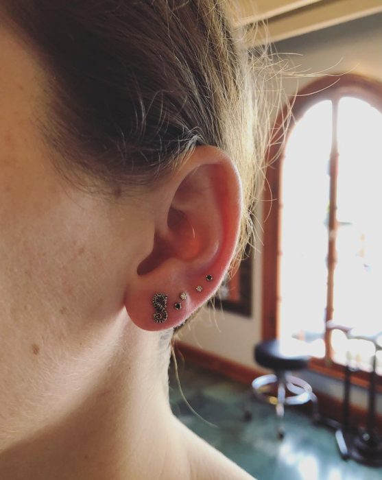 Oreja de chica con más de un piercing