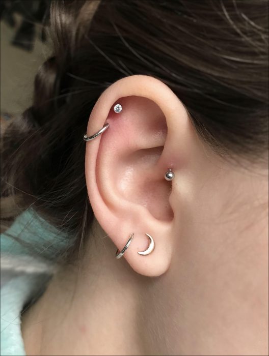 Oreja de chica con más de un piercing