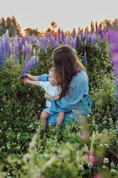 mamá e hijo jugando con flores en el campo