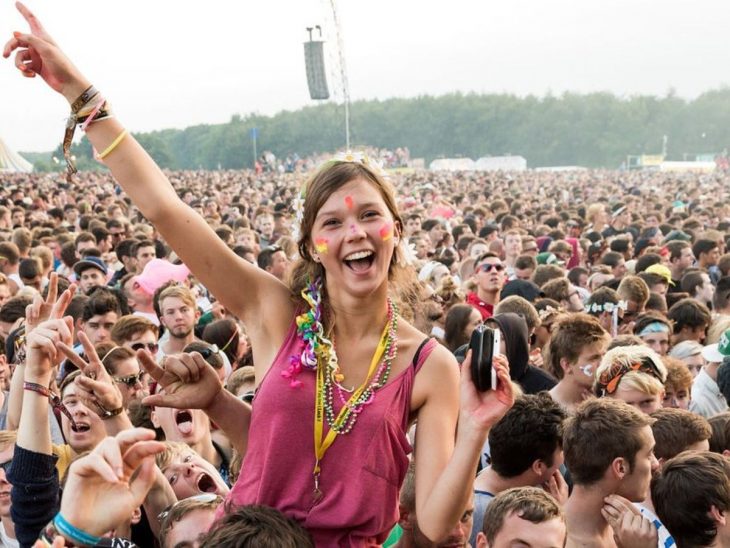 mujer sonriendo arriba de piernas de hombre en concierto 