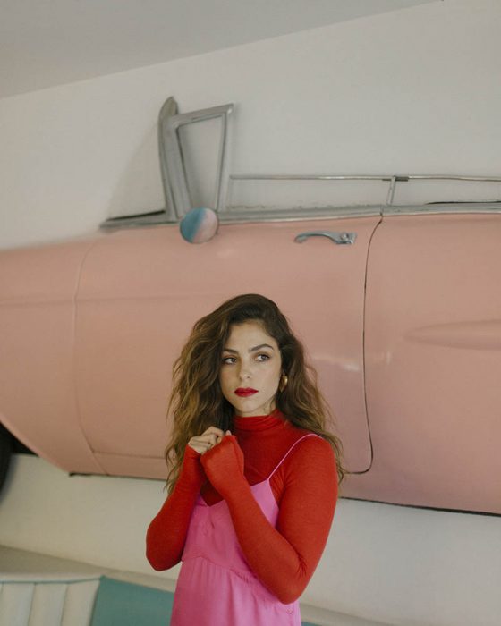 mujer con vestido rosa y blusa roja con cuello de tortuga 