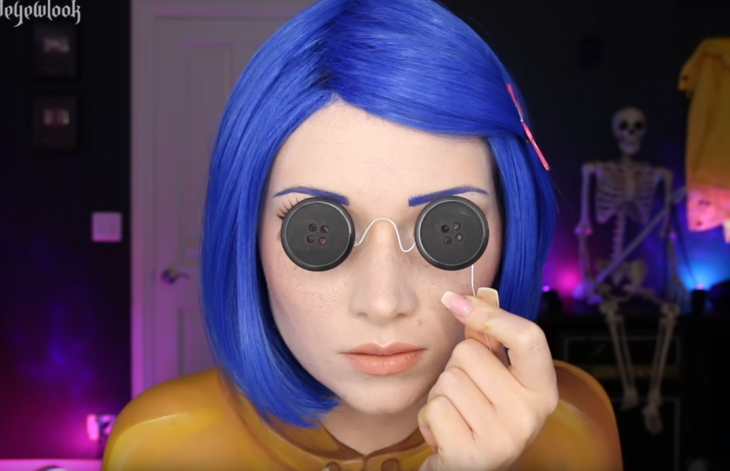 mujer con cabello azul y botones en los ojos 