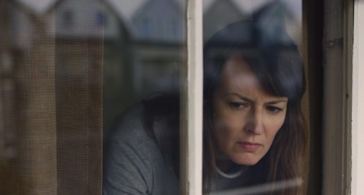 mujer asomada por la ventana con cara de miedo 