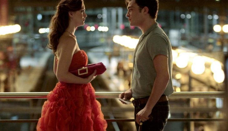 mujer con vestido rojo y bolso y hombre blanco con camisa 