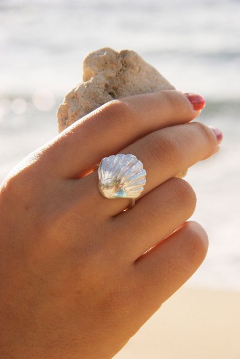 Mano de mujer con anillo de concha