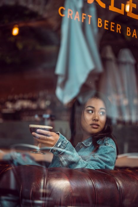 chica bebiendo cerveza en una copa de cristal