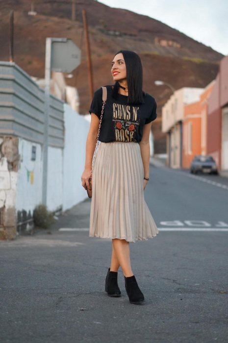 Chica en la calle con playera de Guns and roses, falda plisaba beige y botines negros