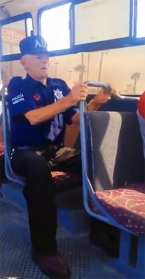 Viejito con uniforme de la policía municipal viajando en el transporte público