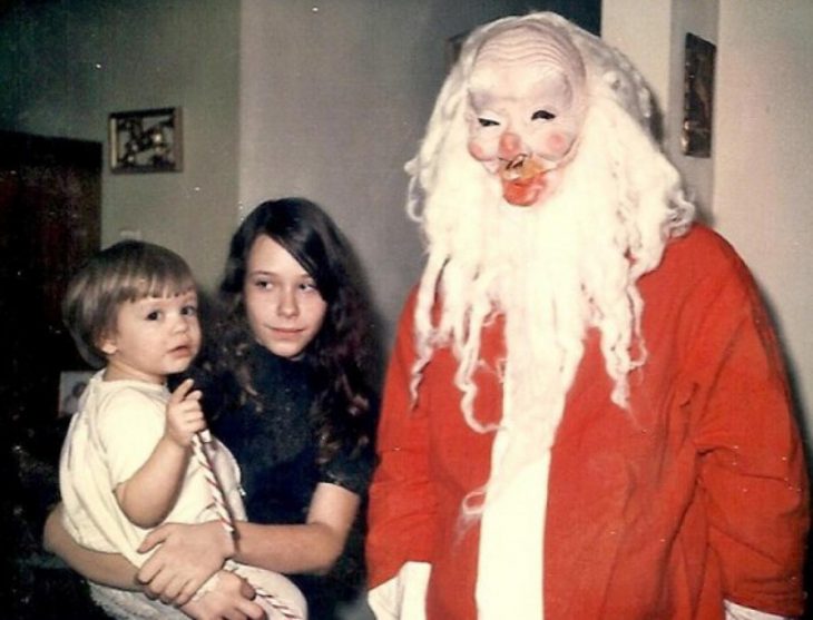 Santa Claus que da miedo al lado de dos niños