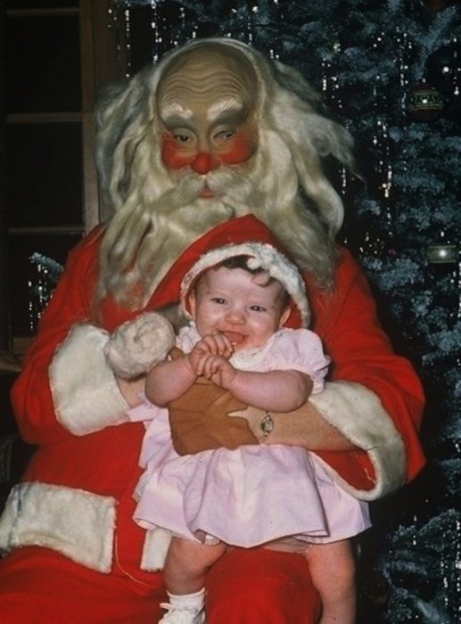 Santa Claus que da miedo cargando a una niña