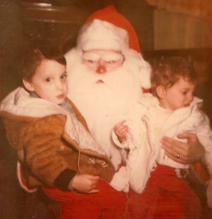 Santa Claus que da miedo cargando a dos niños