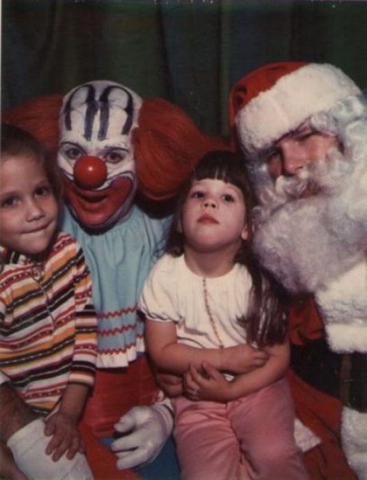 Santa Claus que da miedo junto a un payaso cargando a dos niños