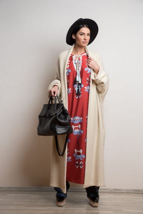 Mujer usando un vestido boho, pantalón de mezclilla y abrigo largo