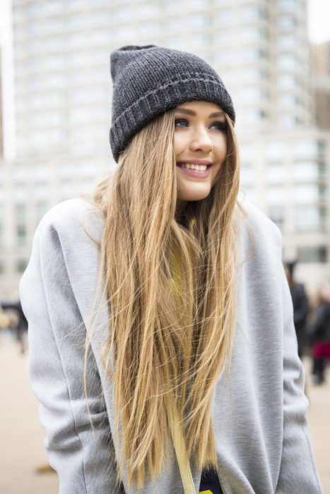 Chica de cabello rubio y largo con gorra de invierno y sudadera