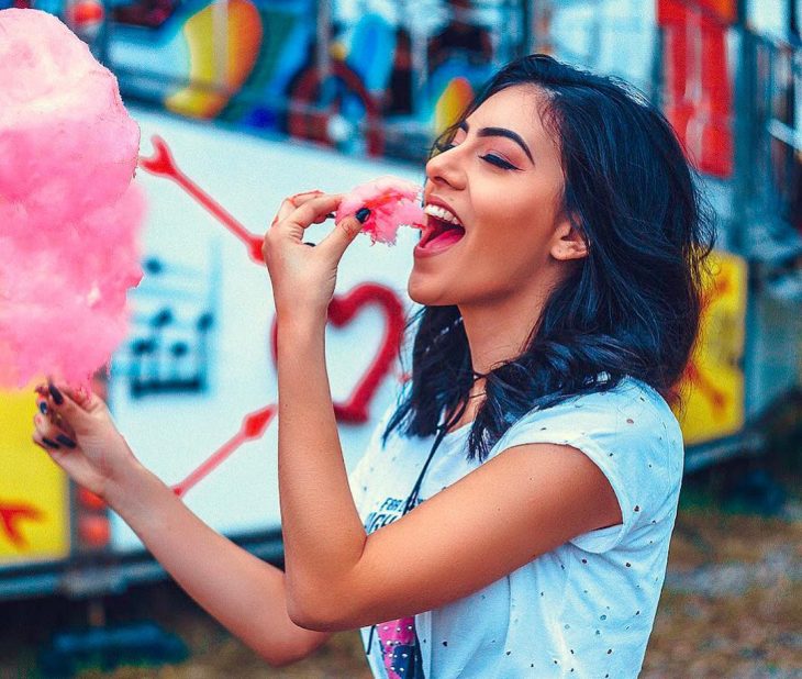 Chica feliz comiendo algodón de azúcar